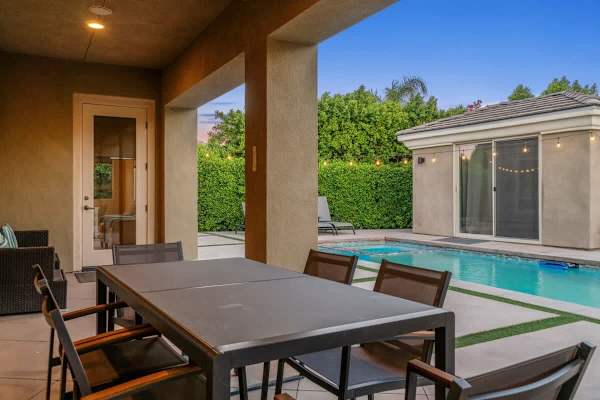 Dine alfresco with string lights and hedge privacy nightly.