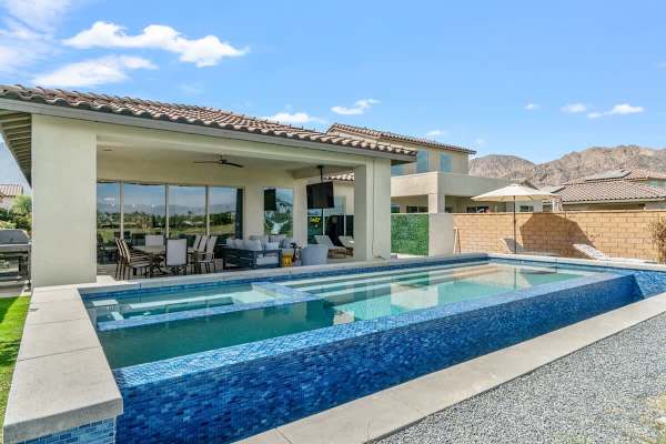 Lap pool stretches toward championship greens—blue tile sparkles against desert landscape and sky.