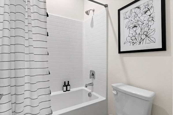 Tub-shower combo with geometric tile accent—modern fixtures and art make this bath shine.