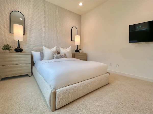 Third bedroom with upholstered platform bed—sconces free up nightstand space for books and coffee.