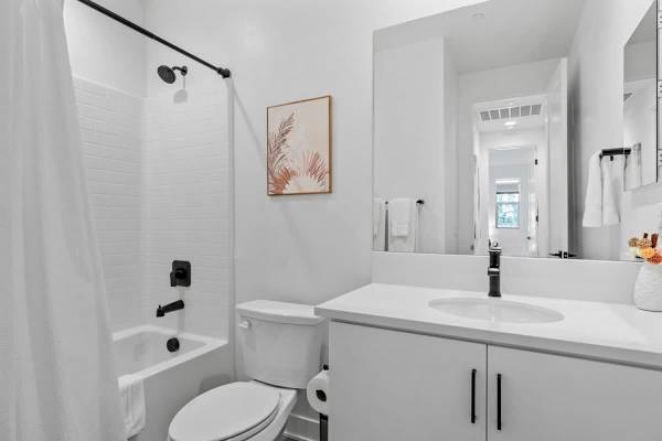 Guest bath with tub-shower combo—white vanity and subway tile.