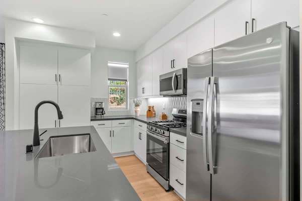 Undermount sink with modern black faucet—white cabinets and stainless appliances shine throughout.