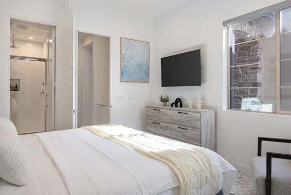 Comfortable bedroom with TV and dresser for a relaxing home away from home.