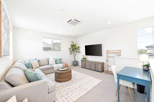 Upstairs loft area with a spacious seating area, TV, and workspace.