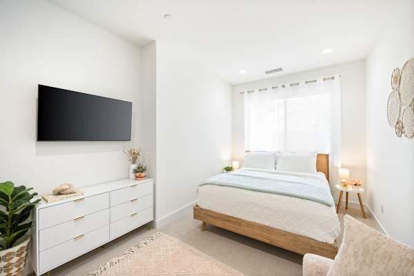 Simple, clean bedroom setup with a comfy queen bed and a TV.