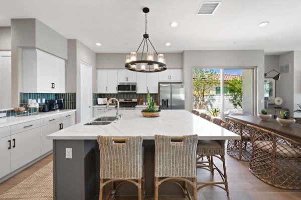 Kitchen with white cabinetry, island seating, and stainless appliances.