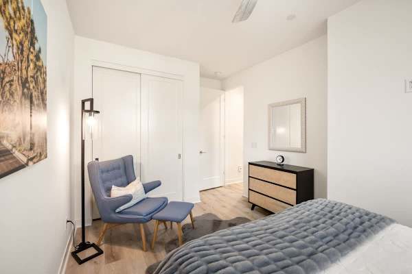 Guest bedroom offers a queen bed, reading chairs, and closet space.