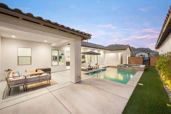 Backyard at sunset with pool, covered patio, and mountain backdrop.