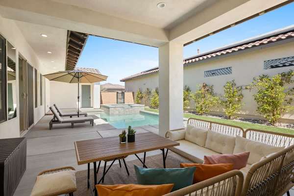 Covered patio with outdoor dining opens to the pool and yard.