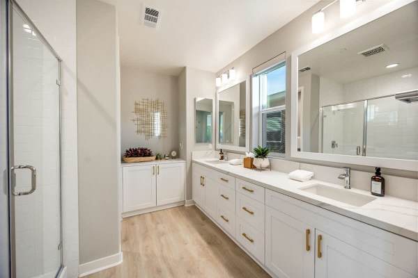 Master suite bathroom featuring a spacious step-in tile shower, dual vanities, and a private restroom.