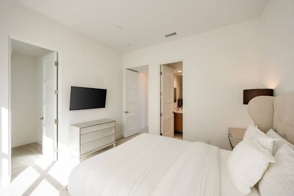 Another comfortable bedroom with a wall-mounted TV and its own bathroom just steps away.