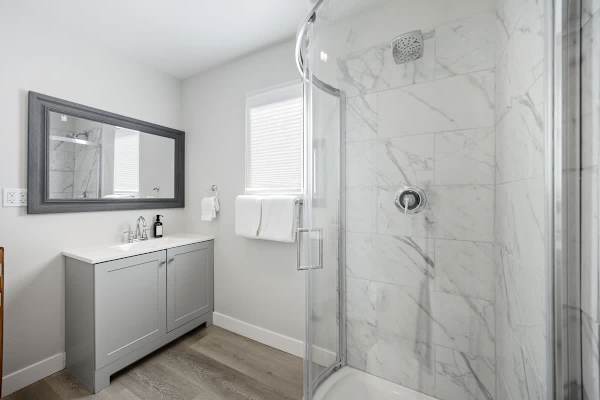 Marble-style shower upstairs—clean and modern for bedroom four guests to refresh.