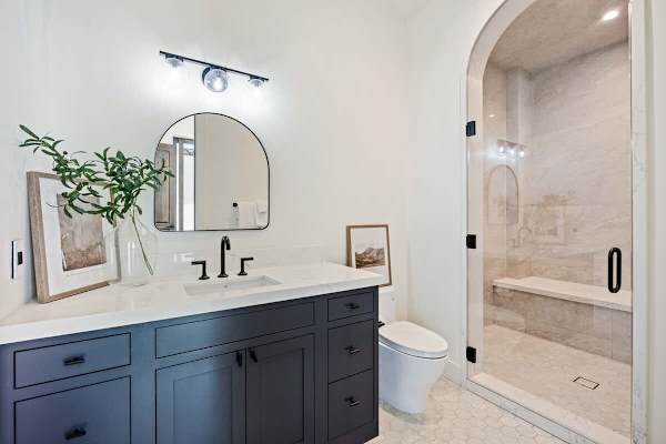 Chic bathroom with a navy blue vanity and curved mirror detail.