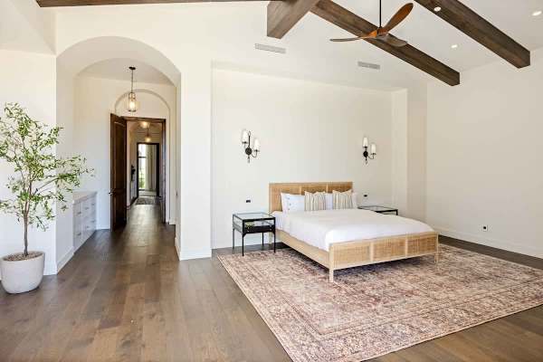 Spacious primary bedroom with vaulted ceilings and wood beam details.