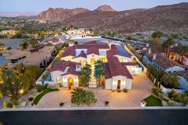 Your sprawling desert compound lit up against the dramatic mountain backdrop.