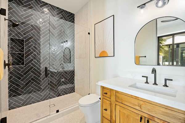 Striking herringbone tile and warm wood vanity in the guest bath.