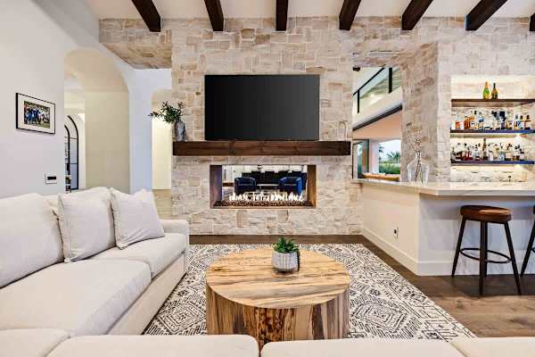 Dramatic stone fireplace anchors the living room with a flat-screen TV mounted above.