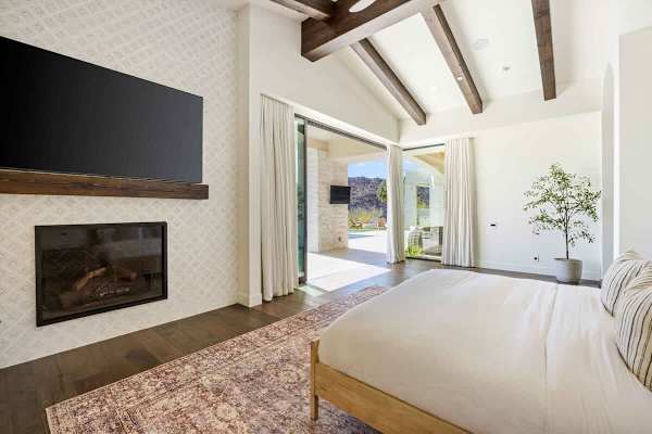 Modern fireplace connects the bright interior to the covered patio beyond.