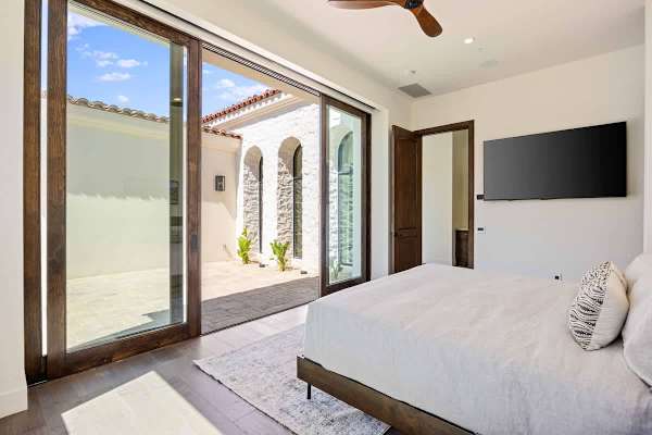 Bright bedroom suite with oversized glass doors to a quiet outdoor space.