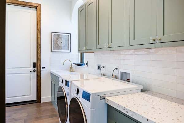 Spacious laundry with sage green cabinetry and plenty of counter space.