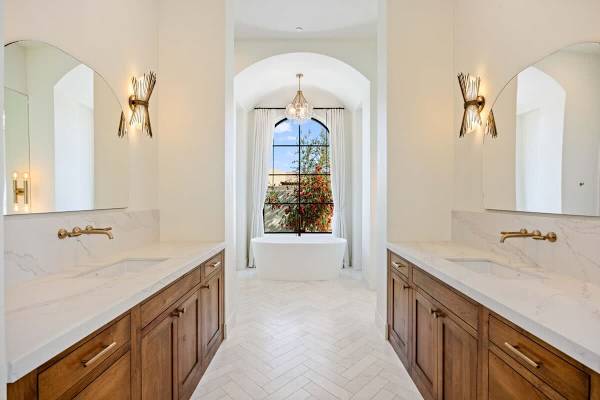 Elegant bathroom with dual vanities and an arched window centerpiece.