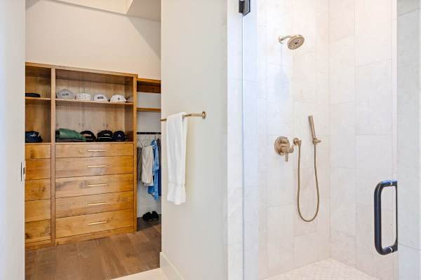 Walk-in closet with custom wood cabinetry opens to the spa-like bathroom.