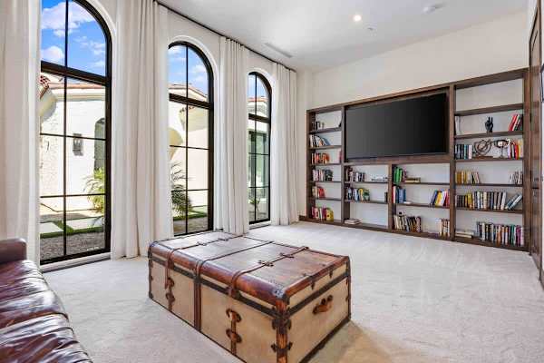 Fourth bedroom features dramatic arched windows and built-in shelving with a TV.