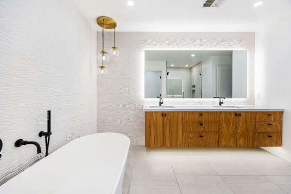 Wood vanity with backlit mirror and freestanding tub.