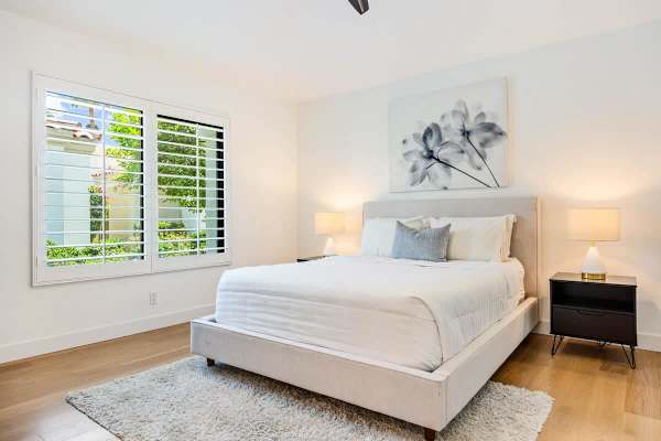Suite 2 with floral art and plantation shutters—soft grays create a calming guest retreat.