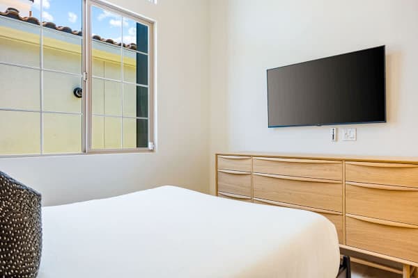 Third bedroom with dresser, and TV offers a simple and comfortable space for restful sleep here.