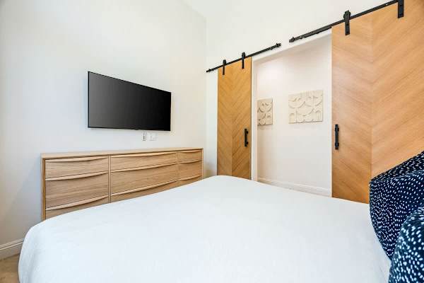 Queen bedroom with wall-mounted TV and dresser gives everyone their own comfortable space to rest.