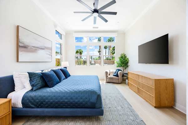King bedroom features ceiling fan, TV, and bright windows overlooking the pool and mountains.