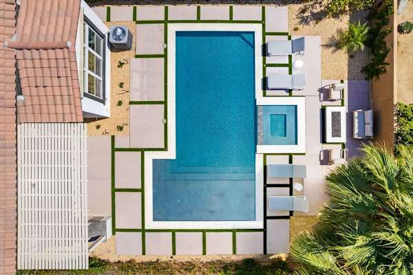 Aerial view of the private pool with tanning shelf, spa, and patio loungers.