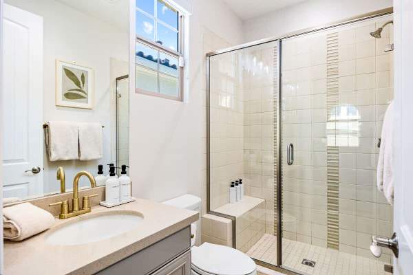 Suite 2 bathroom features a walk-in shower, gold fixtures, and clean lines.