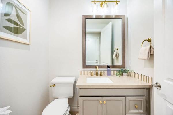 Half bathroom near the main living area with gold fixtures and vanity makes hosting guests effortless.