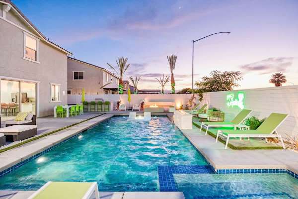 Pool and spa illuminated at dusk with palm trees.