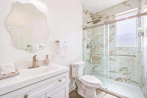 Full hallway bathroom with shower combo and clean white vanity.