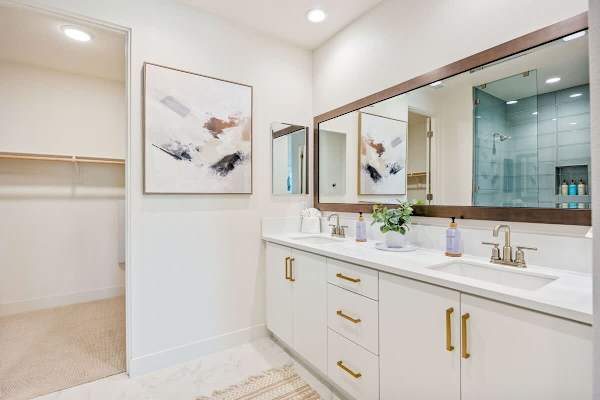 The primary bathroom has double sinks with plenty of counter space and gold fixtures.