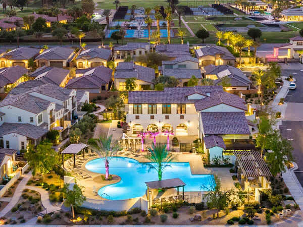 An aerial view of the Signature community showing the pools and homes all lit up at night.