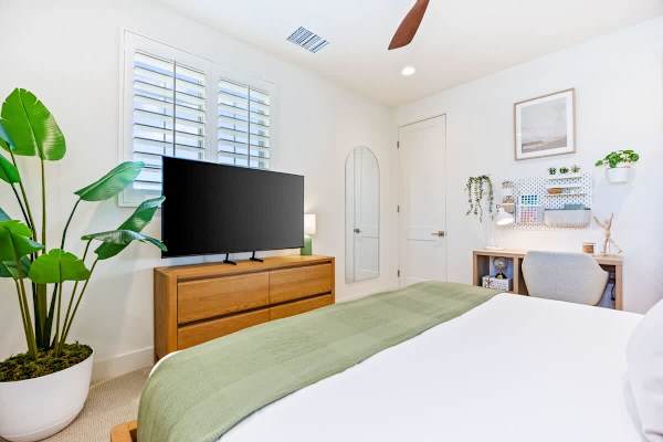 This bedroom doubles as a workspace with a desk and walk-in closet storage.