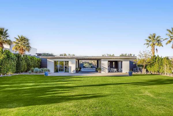Open green lawn with clubhouse and shaded seating areas