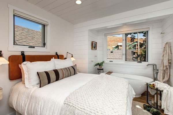 Lofted bedroom in detached guest suite, with a queen bed next to standalone bathtub.