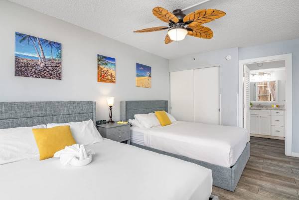 2 Queen-size beds in the living room with a ceiling fan