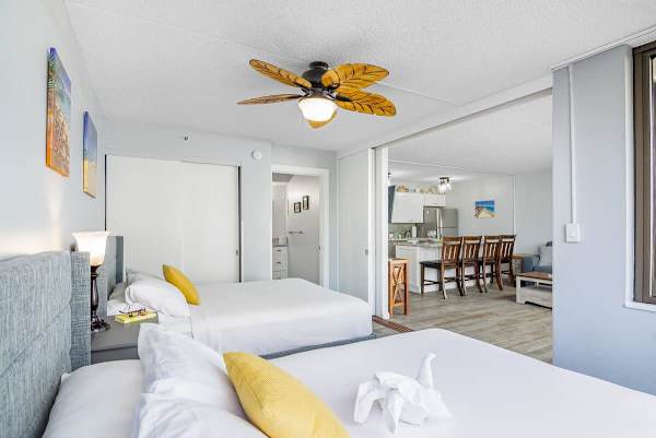 2 Queen-size beds in the living room with a ceiling fan