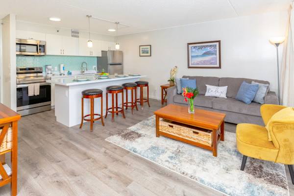 An overview of the living room, kitchen, and dining area with 4 bar stools.