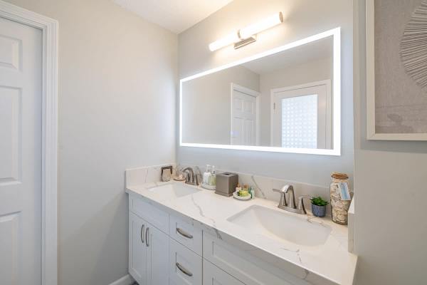 Well-lit bathroom vanity with a double sink and Bluetooth mirror.