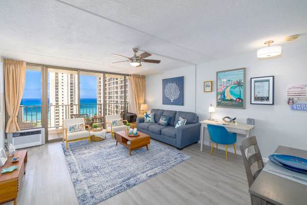 An overview of your living room with a queen-size pull-out sleeper sofa, ceiling fan, window AC, and a stunning ocean view.