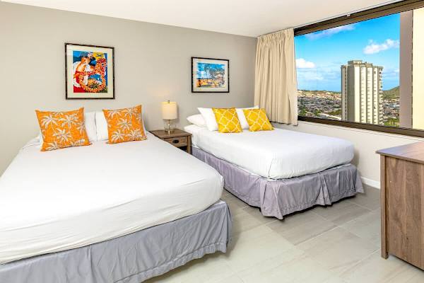Bright bedroom with two beds and a city view from the window