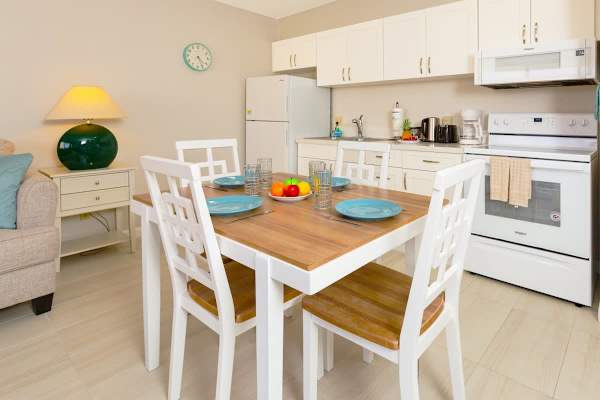Bright kitchen and dining area with white cabinetry and a wooden table set for four.