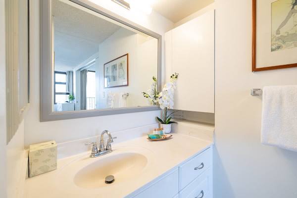 Bright bathroom vanity with a large mirror and fresh orchid accents